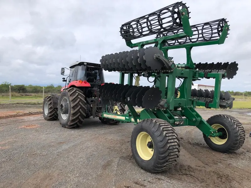 Tractor con una rastra de discos plegada para transporte, en un camino rural