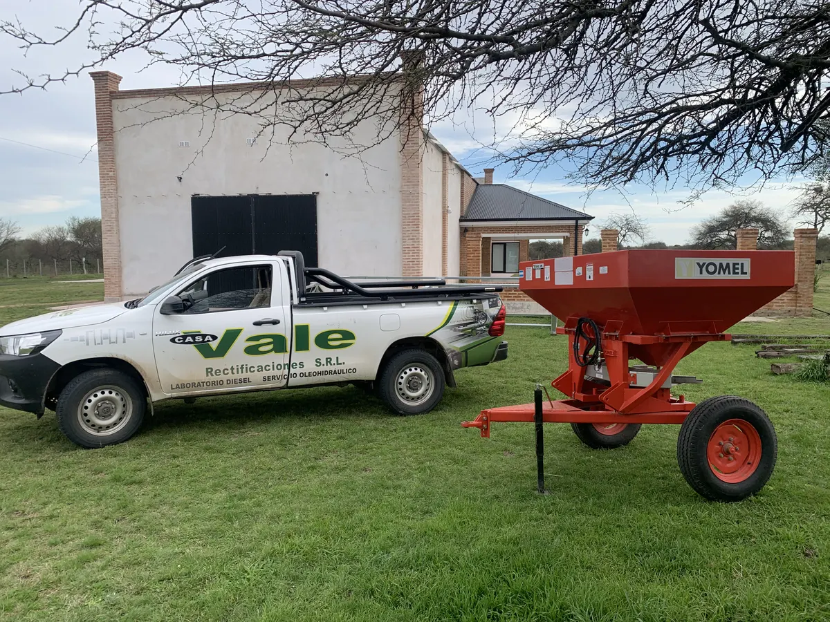La camioneta de Casa Vale junto a una fertilizadora Yomel, frente al galpón de un establecimiento